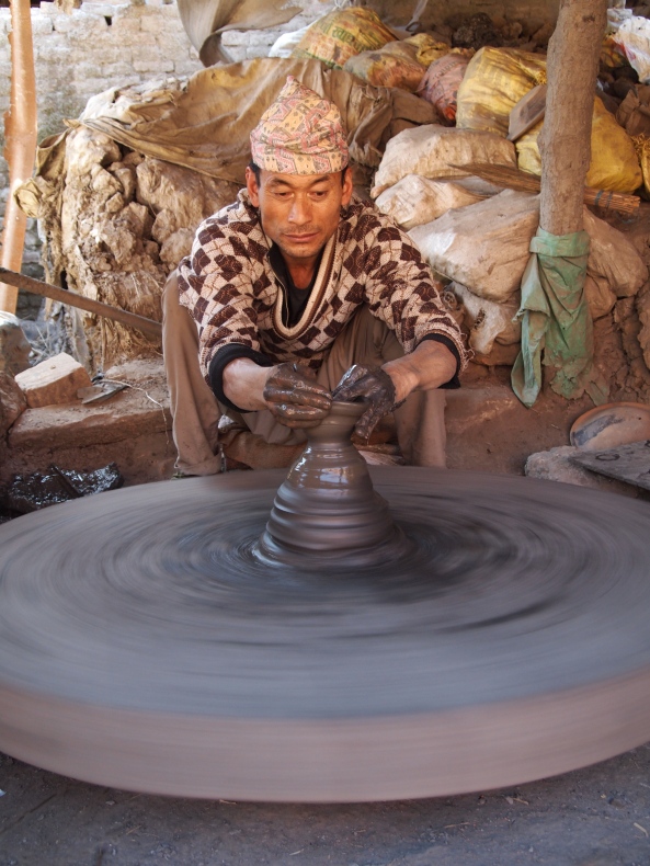 a potter using the traditional hand-powered wheel
